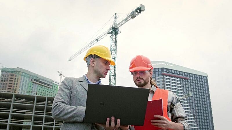 Building,Contractors,Using,Portable,Computer,During,Site,Inspection